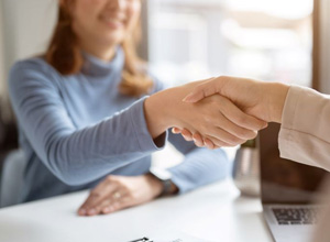 Two people sitting at desk and shaking hands