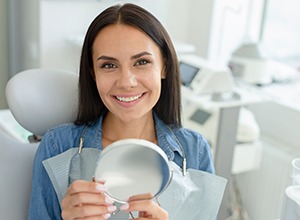 Happy dental patient holding a mirror