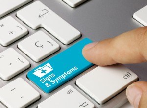 Person touching computer key that says “signs and symptoms”