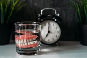 Dentures sitting next to clock on nightstand